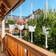 Close-up of white macrame plant hanger with green plant and hand-woven design