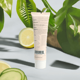 Tube of skincare product with lemon and cucumber slices on a light background