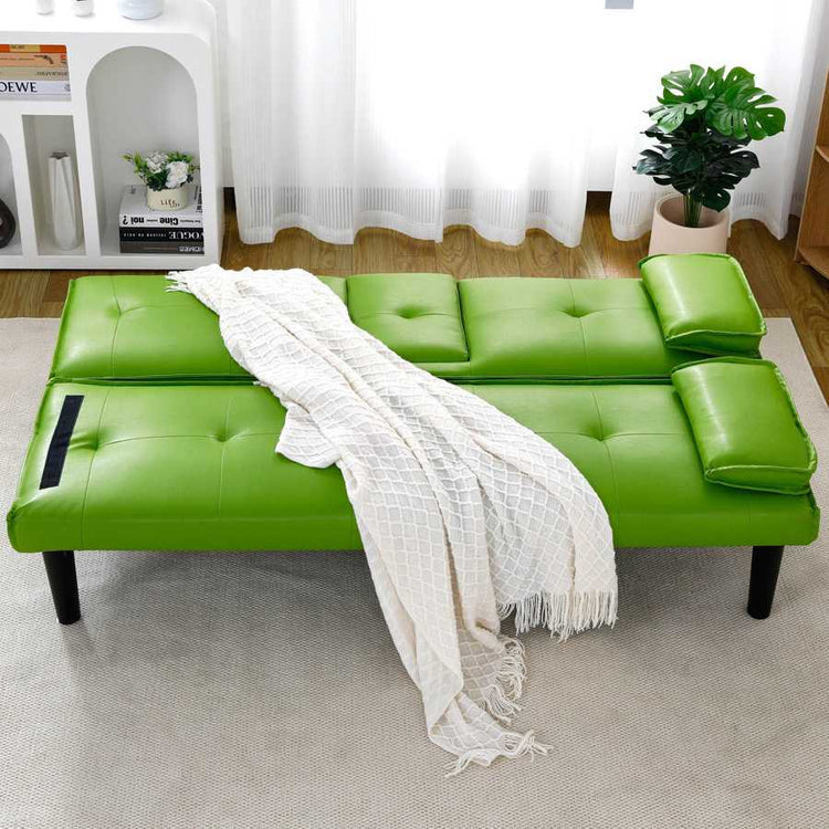 Green sofa bed with a white blanket in a room with a bookshelf and plants.