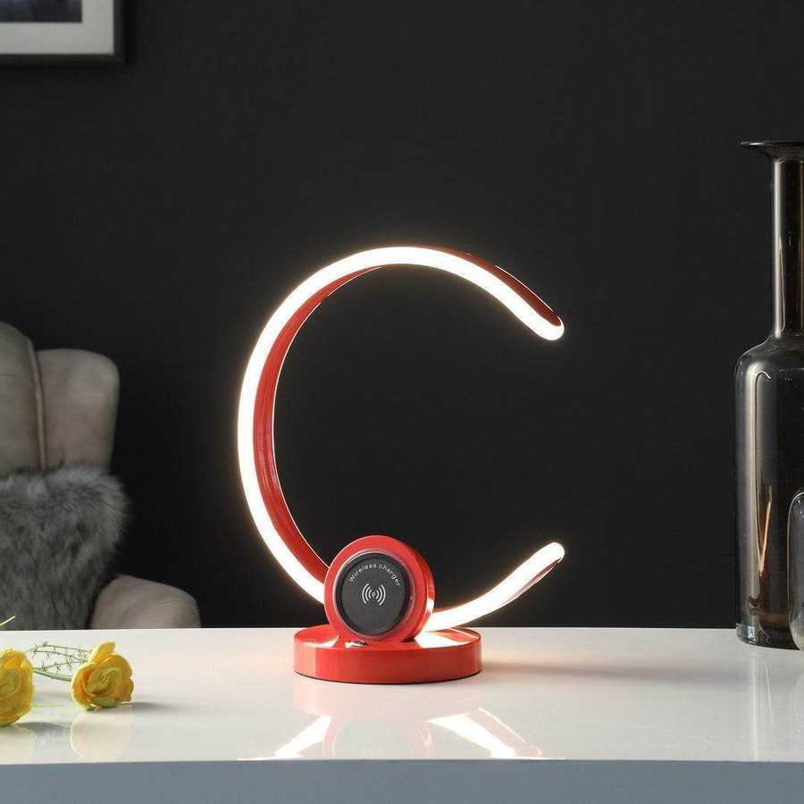 Modern LED desk lamp with a red base on a white surface, dark background