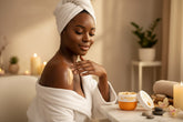 Woman applying cream to her shoulder with a warm, blurred background